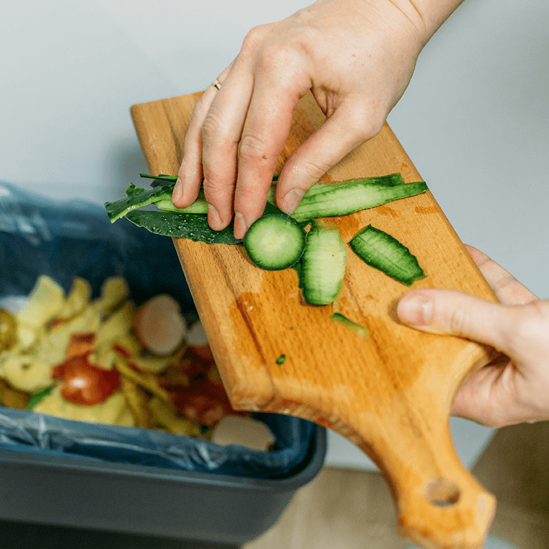 Vegetable scraps being placed in kitchen waste bin