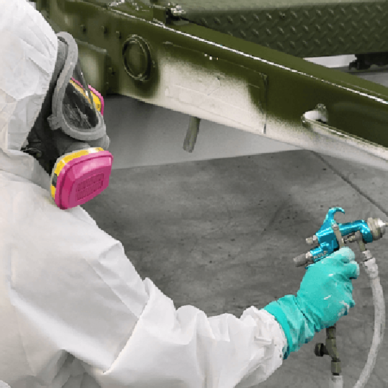 Link, a painter trainee in proper safety gear practices spray application on a disassembled auto part
