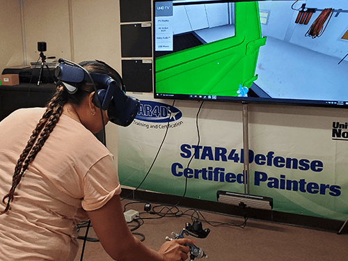 Woman wearing virtual reality googles using the VirtualPaint painter training system developed by painter training experts at the Iowa Waste Reduction Center