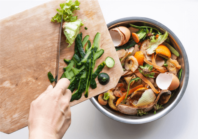 person pushing food scraps into a bucket of food scraps for disposal