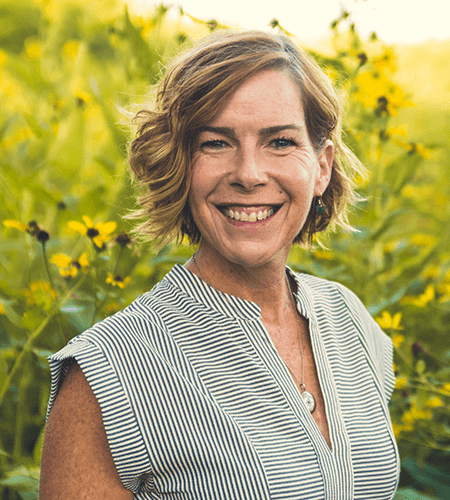IWRC Program ManagerJennifer Trent stands before a field of yellow flowers.