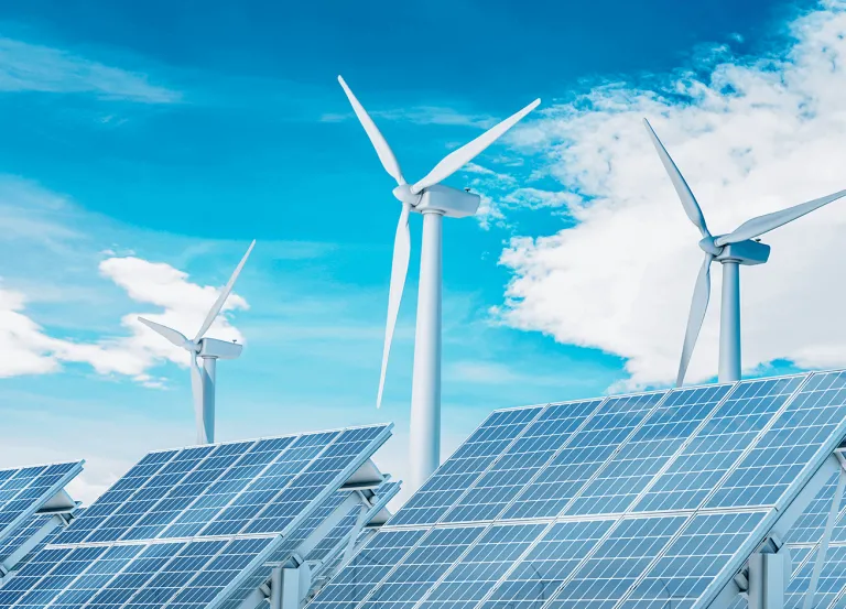Windmills and solar panels against blue sky