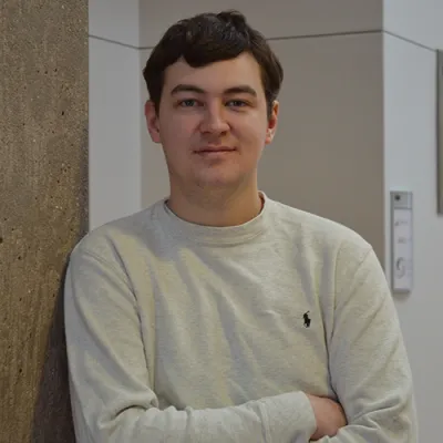 Link, Young man in cream sweater leaning against a cement pillar, profile page