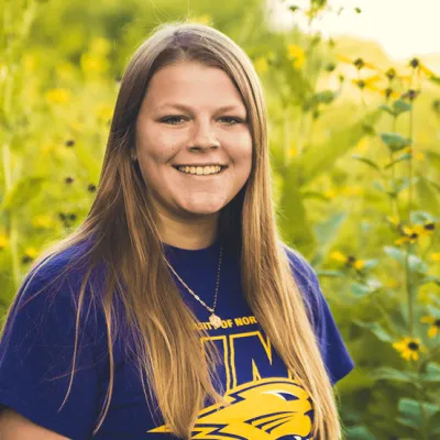 Link, Environmental Specialist Jordan Burrows standing before field of yellow flowers, profile page