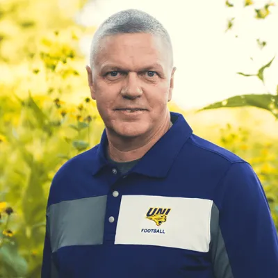 Link, Mark Harrington standing before field of yellow flowers, profile page
