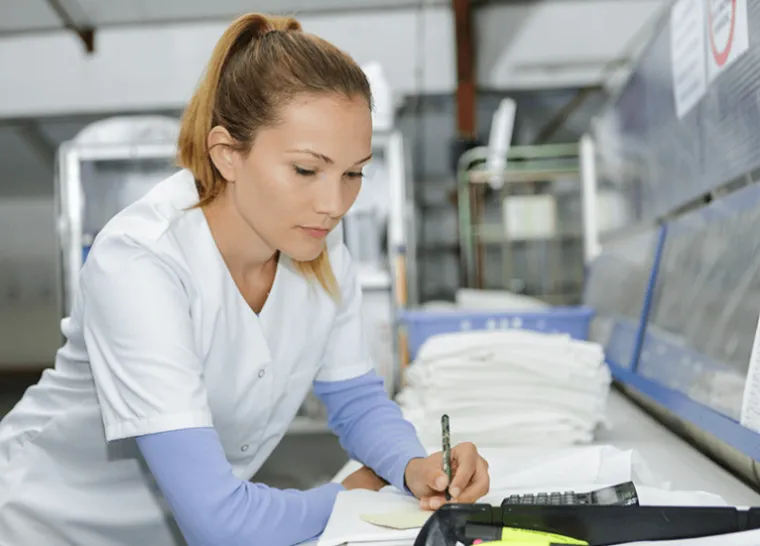 Employee at drycleaning facility fills out paperwork.